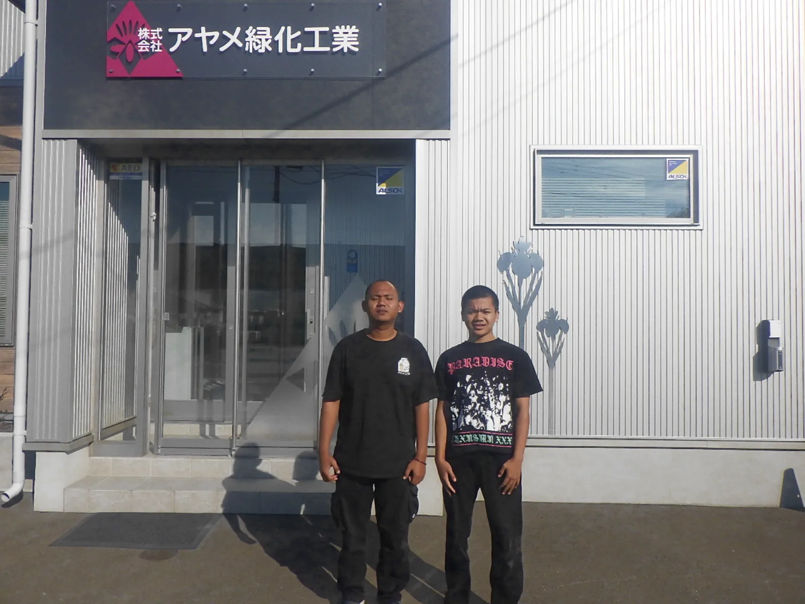 Two new team members standing in front of AYAME's Kitami branch