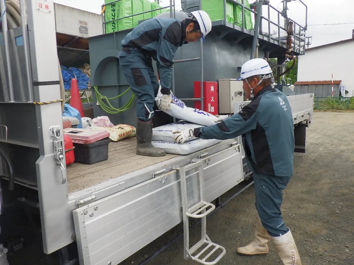 地面からトラックの荷台へ資材を持ち上げる作業