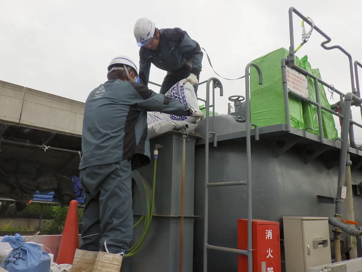 トラックの荷台から機械上部へ資材を持ち上げる作業